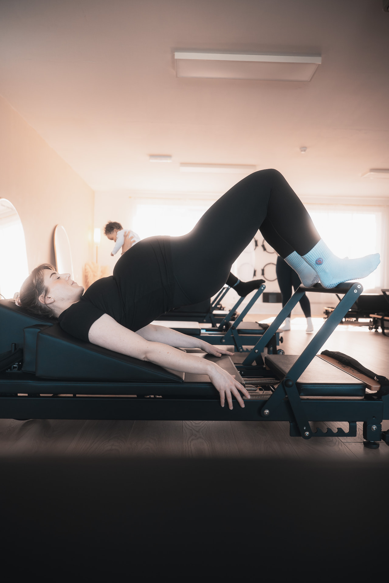 Pregnant client performing a supported bridge on the reformer