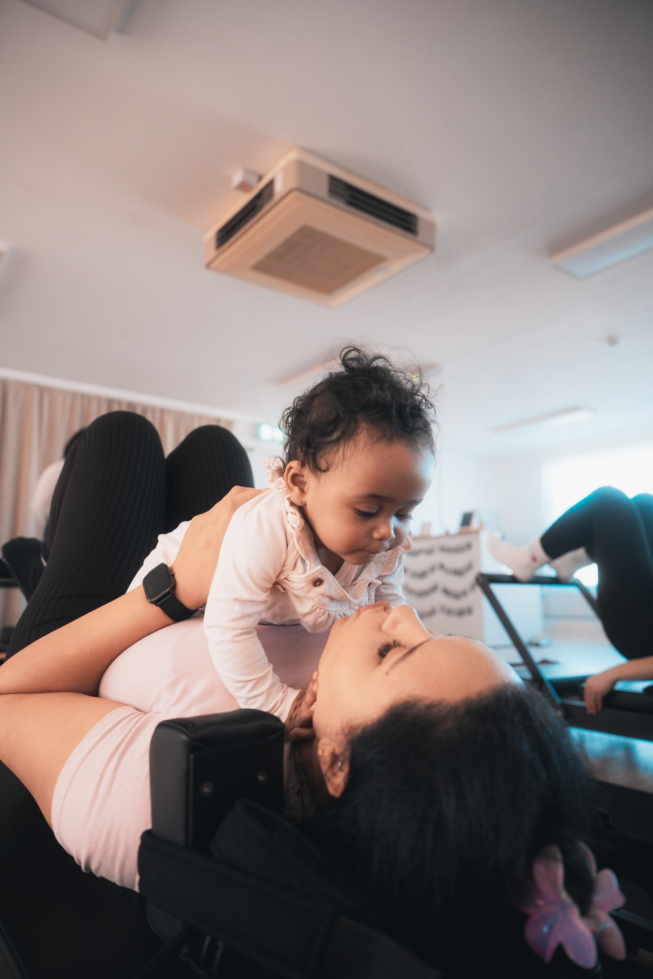 Parent lifting their baby during a Baby & Me mat Pilates class